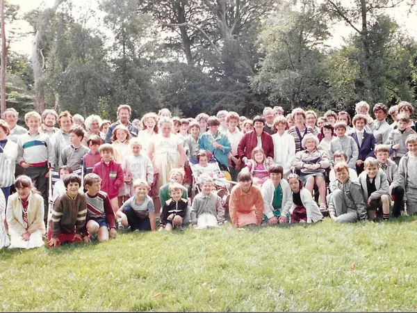 A large group photo of the original Dolphin Swimming Club members and families gathered outdoors