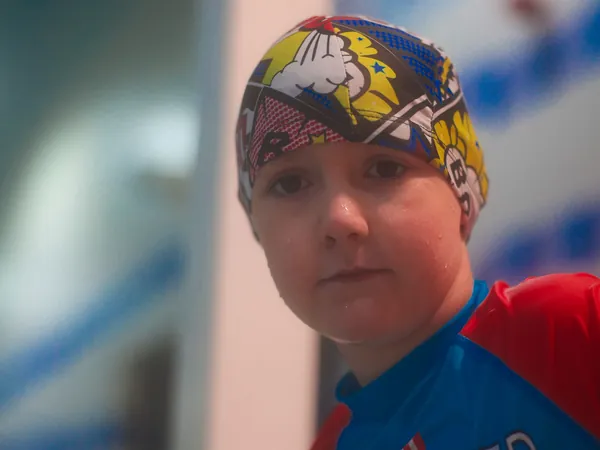 A boy in a colourful swim cap at the poolside