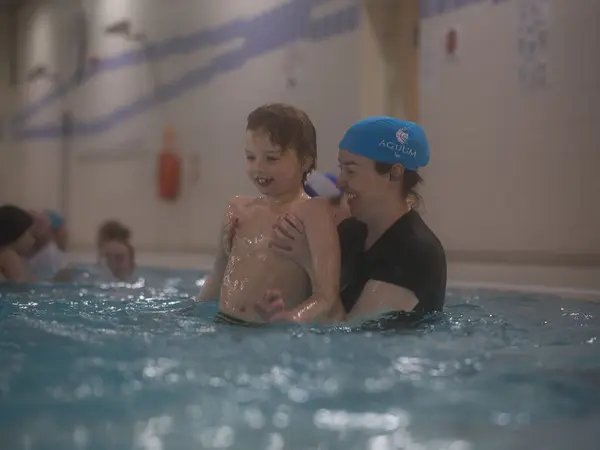An instructor sharing a laugh with a boy during a swimming session