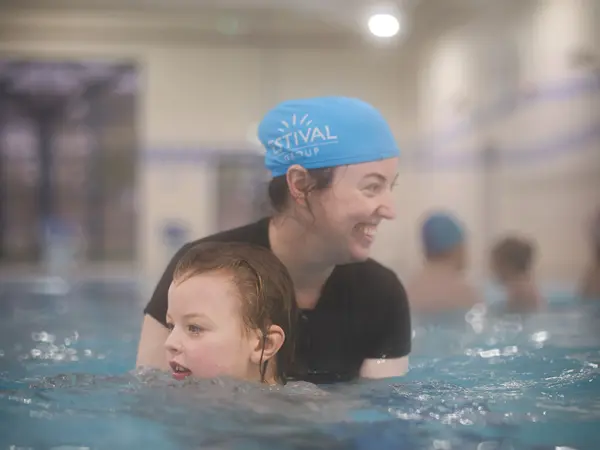 An instructor chatting with a child in the water