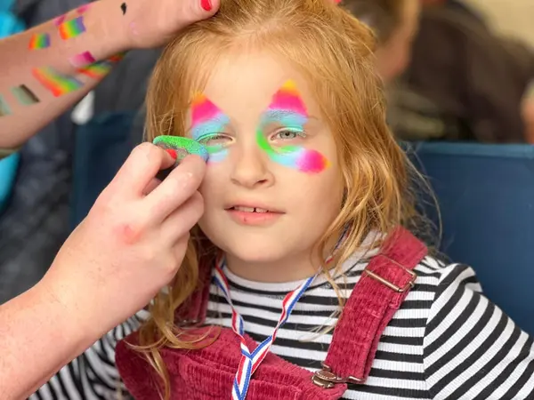 A child having colourful face paint applied