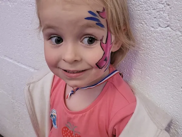 A smiling girl with pink face paint at the farm