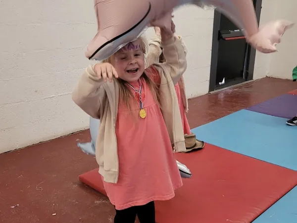A girl wearing her medal playing under an inflatable dolphin