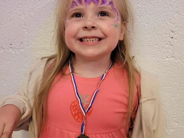 A girl with face paint proudly wearing her medal
